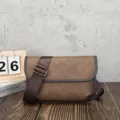 Close-up detail of retro brown messenger bag, soft leather texture, adjustable strap. - Khaki and Grey