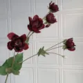 Primo piano di fiore artificiale, testa di fiore rosso scuro e foglie verdi, decoro. - Borgogna