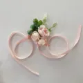 Detailed shot of pink artificial flower corsage with ribbon for wedding party photography. - Wrist Corsage