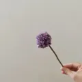 Close-up detail shot of a single artificial purple chrysanthemum flower held by hand for decor. - Purple
