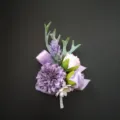 Gedetailleerd overzicht van de elegante paarse kunstbloemen boutonniere voor herenkostuum. - Paars