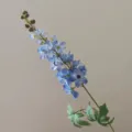 Detailed close-up of a single blue artificial delphinium branch with petals and buds. - Blue