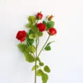 Close-up detail of 5-head artificial red rose branch with green leaves for home decor. - Red
