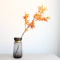 Gedetailleerd takje met kunstmatige esdoornbladeren en herfstkleur in een grijze glazen vaas. - 82cm / Oranjegeel