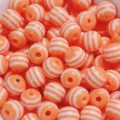 Vue détaillée de perles rondes en résine rayée, style bonbon coloré pour bijoux DIY. - Orange