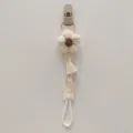 Detail shot of a cute handmade knitted flower pacifier clip strap with soft fabric. - Beige Floral
