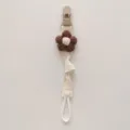 Close-up detail of a handmade knitted flower baby pacifier clip with secure fabric strap. - Brown Floral