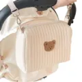 Nahaufnahme der beige gesteppten Kinderwagen-Tasche mit einem süßen Bären-Aufnäher. - S / Bärenkopf