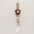 Detail view of handmade knitted flower pacifier clip with plaid fabric and clip. - Brown Floral Plaid