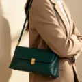 Green leather baguette shoulder bag detail featuring elegant metal clasp and sleek design. - Green