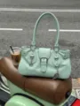 Detail view of the light green motorcycle handbag with metal buckle and wing charm for street style. - Green