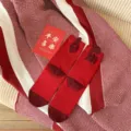Detailed shot of festive red winter mid-tube socks featuring soft cotton fabric and cute flocking details. - Joy (Red)