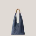 Détail du sac porté épaule en denim avec tissu texturé et poignée en cuir tressé raffiné. - Bleu Foncé