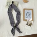 Detail shot of black and white wave pattern silk scarf with magnetic buckle accessory. - Minimalist Style