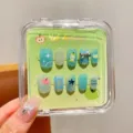 Handgefertigte blaue Künstliche Nägel Detailansicht mit niedlichen Frucht- und Schleifendetails. - Blauer Apfel