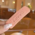 Close-up detail of candy color leather hair clip featuring embossed love pattern, chic minimalist style. - Pink
