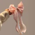 Detailed shot of a large pink organza bow hair clip, elegant ribbon design for women hairstyles. - Pink