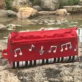 Vista detallada de un estuche creativo con notas musicales y teclado para estudiantes. - Rojo