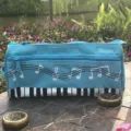 Vista detallada del estuche azul con motivo de notas musicales, costuras limpias y cremalleras dobles. - Azul claro