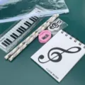 Detalle de set de papelería musical con regla de piano, lápices de notas, goma y libreta. - Set de Música B Serie Notas Blancas