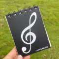 Nahaufnahme Detail eines tragbaren A7 Notizbuchs mit schwarzer Spiralbindung und Noten. - Schwarze Musiknote