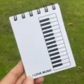 Nahaufnahme des Taschennotizbuchs mit Klavierthema, Spiralbindung und Tastatur-Grafikdesign. - Weißes Klavier