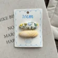 Detailed shot of yellow fabric hair clips with floral and plaid patterns, 10cm size. - Triangle Pair