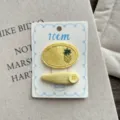 Cream yellow fabric hair clips detail showing pineapple embroidery and cute button decoration. - Button Style
