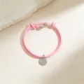 Primer plano detalle de pulsera cordón cuero trenzado rosa con colgante redondo plata. - Cordón Rosa Tono Acero