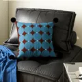Detail shot of blue brown geometric pattern pillow with black pom-poms on dark sofa. - Blueberry Circle Black Pom-pom