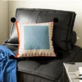 Detail shot of decorative throw pillow with black pom-poms, blue square and pink dash border. - Cyan Blue Stripe Black Pom-pom