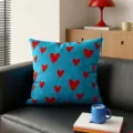 Vista detallada de un cojín azul con estampados de corazones rojos en un sofá de cuero negro. - Funda de Cojín 35x35cm Sin Relleno / Fondo Azul Onda de Corazón