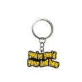 Llavero de goma suave PVC con meme divertido de vaquero occidental y anillo metálico. - Negro Amarillo Eslogan