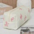 Detailed close-up of quilted cosmetic bag featuring cute pink bow pattern and smooth zipper. - Beige White Base Pink Butterfly