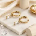Detailaufnahme von goldenen Edelstahl-Ohrringen mit rechteckigen klaren Zirkonen. - Weiß