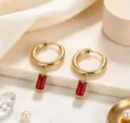 Detailaufnahme eleganter vergoldeter Titanstahl-Creolen mit leuchtenden roten Zirkon-Steinen. - Rot