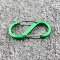 Nahaufnahme des grünen S-förmigen Metall-Karabiners mit Doppelverschluss für Ausrüstung. - Grün