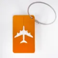 Orange metal luggage tag with hollow airplane design and sturdy steel wire loop for travel bags. - Gold