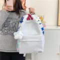 Lässiger grauer Schulrucksack aus Stoff mit bunten Buchstaben und süßem Plüsch-Anhänger. - Mit Anhänger / L / Off-White