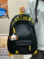 Japanischer minimalistischer schwarzer Rucksack mit grossem Fassungsvermögen, gelben Gurten und Anhänger. - Mit Anhänger / Schwarz