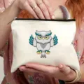 Close-up view showing the zipper detail and cute owl print on the white canvas cosmetic travel bag. - Style 5