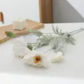 Close-up detail of artificial poppy flowers with white petals and green flocked stems for decor. - White