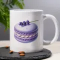Close-up view of the white ceramic coffee mug featuring a purple macaron and lavender print. - Style 3