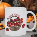Detailed close-up of a white ceramic coffee mug featuring a cute tomato basket print. - Tomato