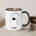 Detailed view of white ceramic coffee mug with black handle, featuring minimalist art and morning text. - Design 2
