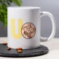 White ceramic coffee mug with diverse hands illustration and letter U for office daily use. - 4
