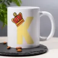 Detailed shot of white ceramic coffee mug featuring custom letter K and crown design. - 8