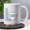 Close-up shot of white ceramic coffee mug featuring cute love design on slate desk top. - 11