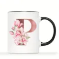 Nahaufnahme einer weißen Keramik Tasse mit floralem Buchstaben P und schwarzem Henkel. - Buchstabe P