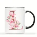 Nahaufnahme einer weißen Keramik Tasse mit schwarzem Henkel und Blumen Design Buchstabe L. - Buchstabe L